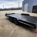 Trailer Hire Brisbane - Black metal flatbed trailer on a concrete surface with a building in the background