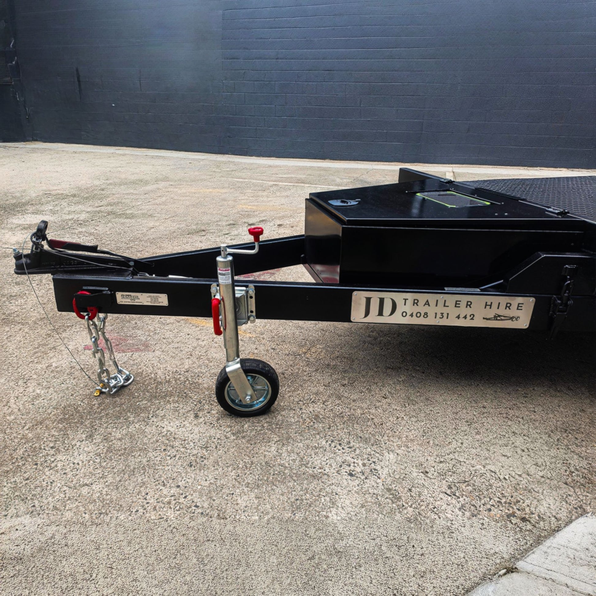 Trailer Hire Brisbane - Black trailer with JD Trailer Hire branding on a concrete surface.