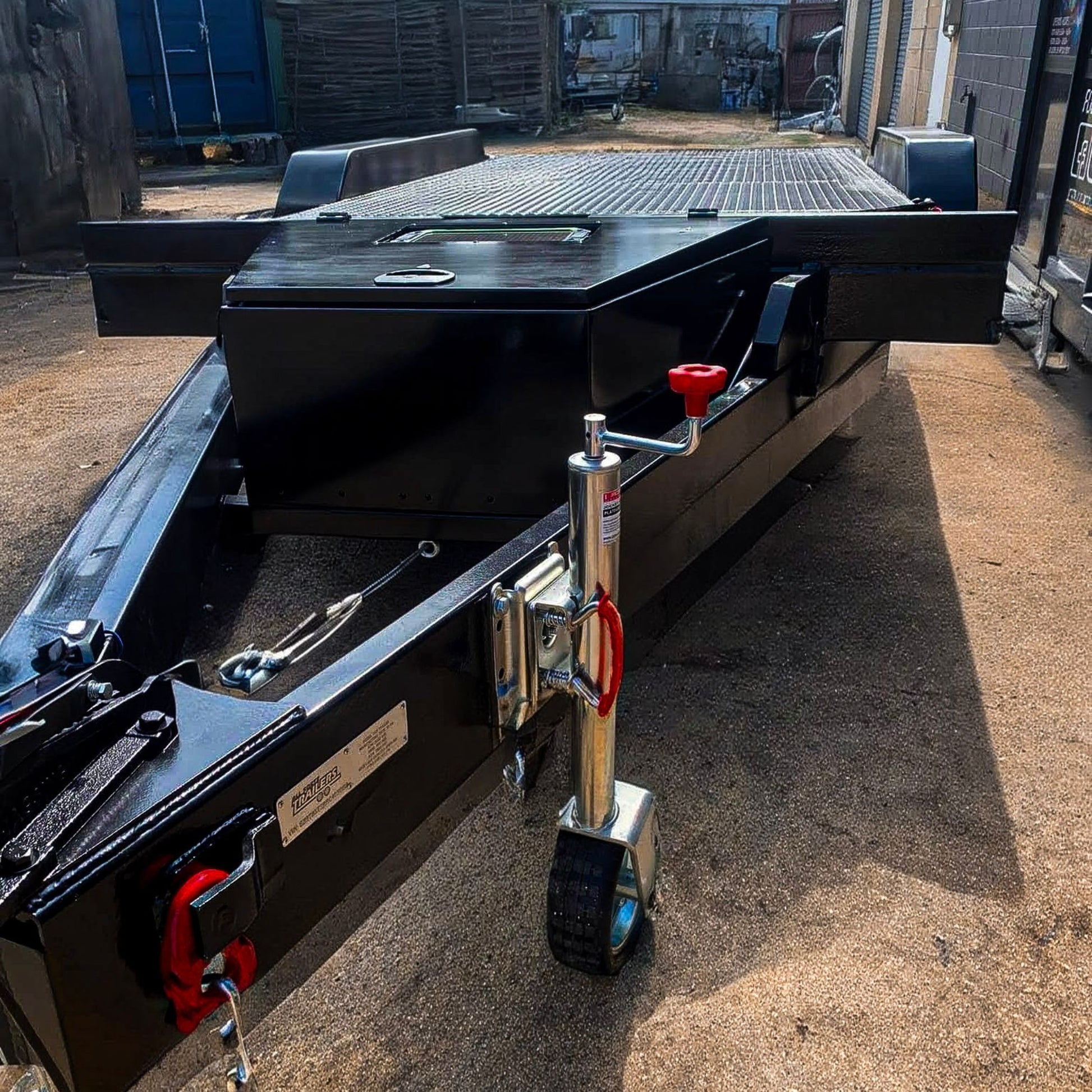 Trailer Hire Brisbane - Close-up of a black trailer with a jack and wheels on a concrete surface.