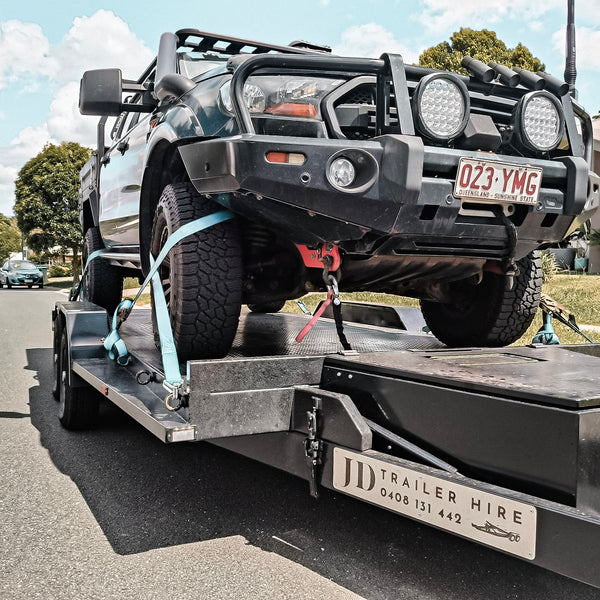 Trailer Hire Brisbane - Truck being towed on a trailer with visible contact information.
