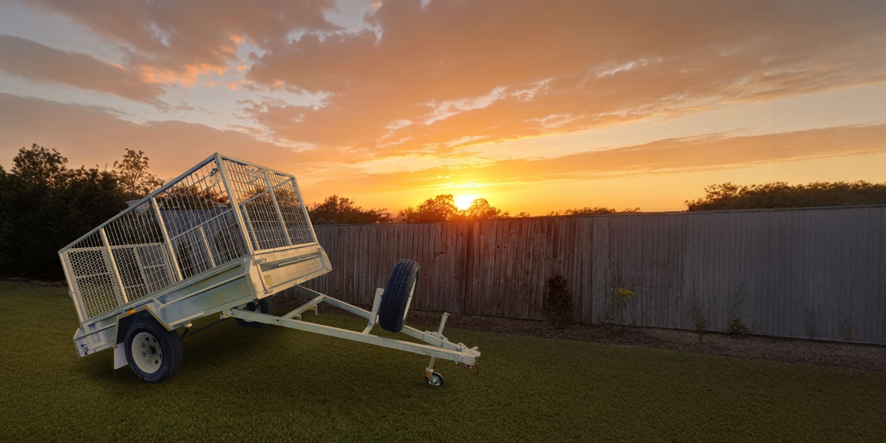 Trailor with cage on grass at sunset with JD Trailer Hire Cage Trailerslider_item_jXYYan