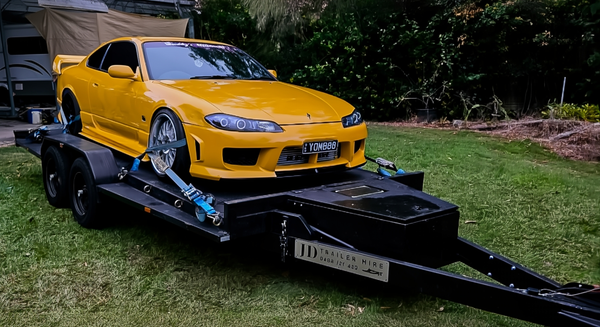 Yellow sports car on a JD trailer Hire Brisbane with a blurred background
